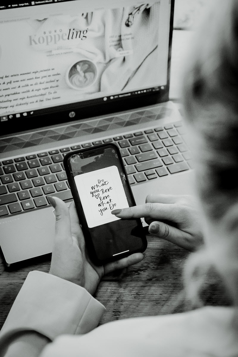 Handgeschreven notitie "Do what you love, love what you do" op een telefoon naast een laptop